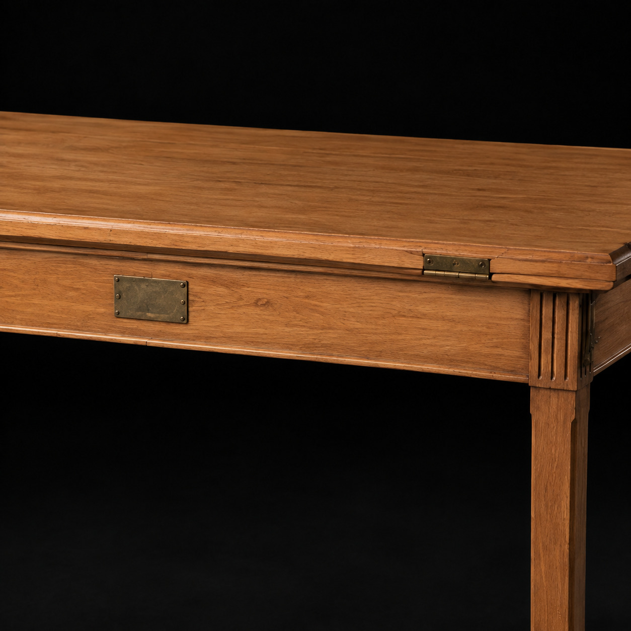 Editorial detail of a plain metal plaque and folding-top hardware on a walnut table.