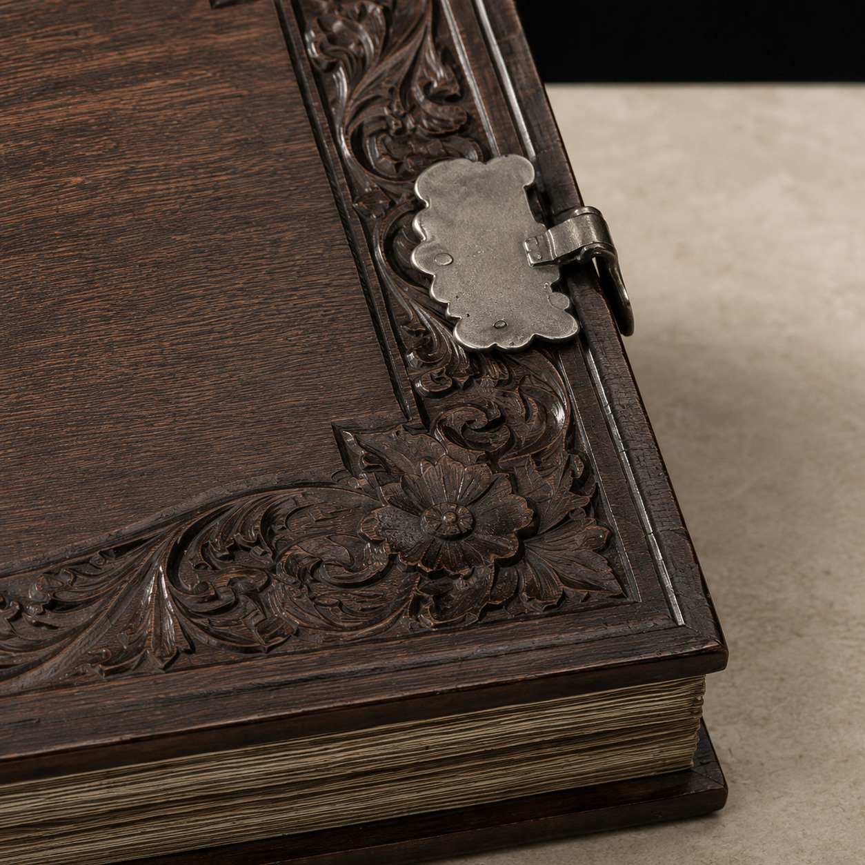 Editorial detail of a silvered album clasp beside carved dark wood and aged paper edges.